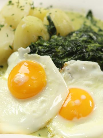 Rahmspinat with fried eggs on a white plate.