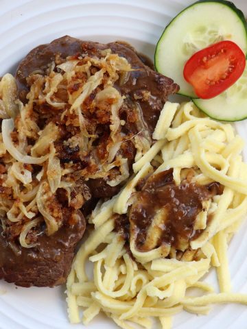 Zwiebel rostbraten on a plate with noodles and onion gravy.